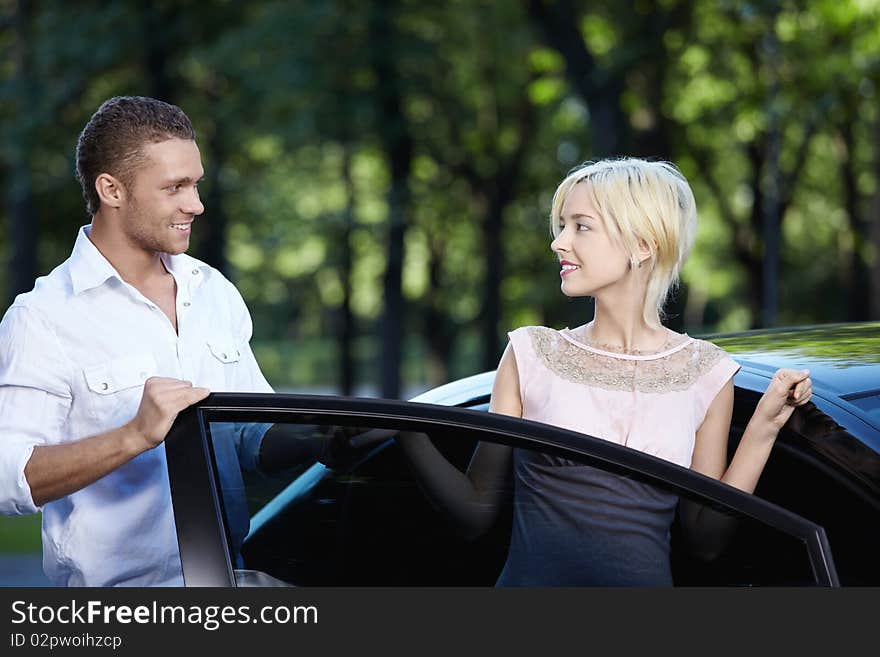 A young man helps a girl get in the car. A young man helps a girl get in the car