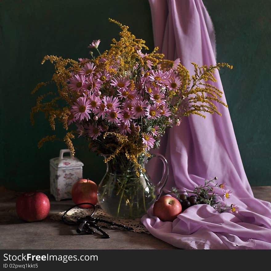 pink flowers stand in a glass jug, fabric, apples and keys, lies alongside. pink flowers stand in a glass jug, fabric, apples and keys, lies alongside