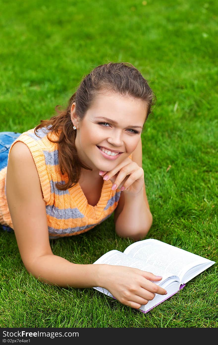 Beautiful young adult lying on grass with book. Beautiful young adult lying on grass with book