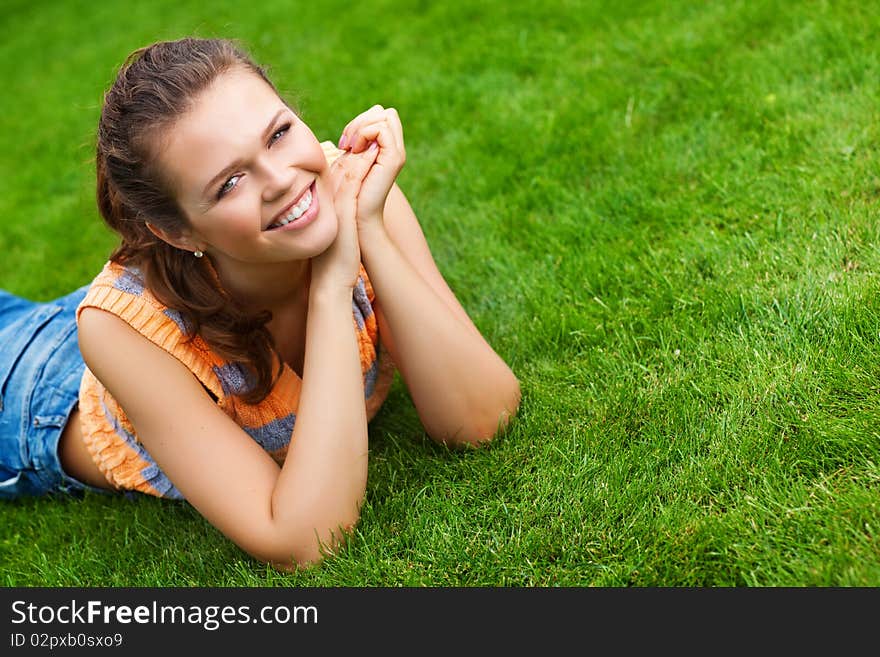 Attractive teenager lying on green lawn smile to the camera. Attractive teenager lying on green lawn smile to the camera