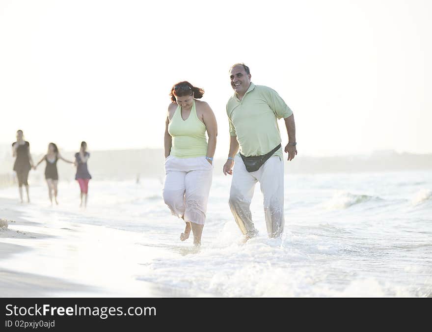 Happy senior mature elderly people couple have romantic time on beach at sunset. Happy senior mature elderly people couple have romantic time on beach at sunset