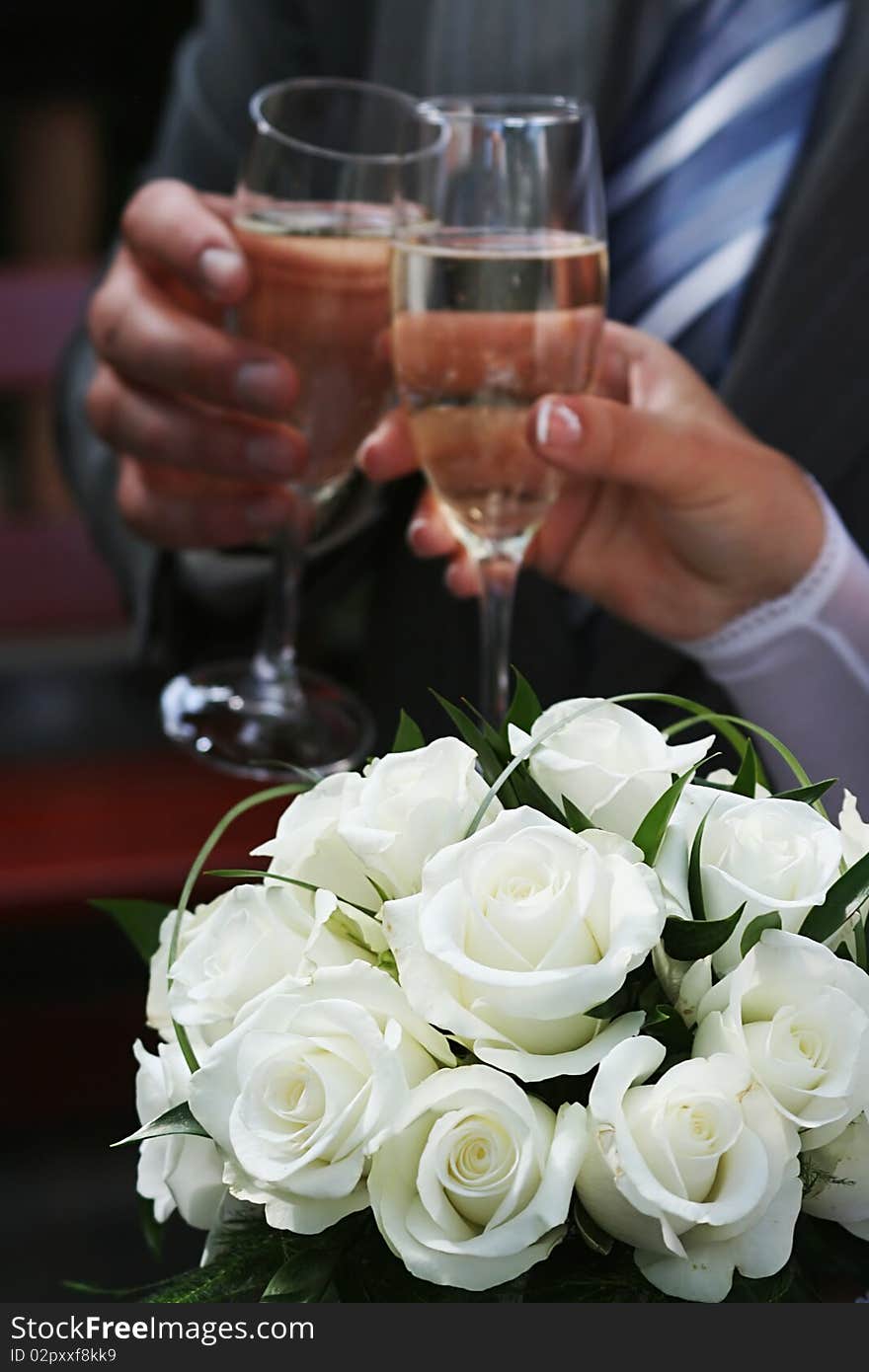 Bouquet of white roses and two hands holding two goblets with champagne. Bouquet of white roses and two hands holding two goblets with champagne.