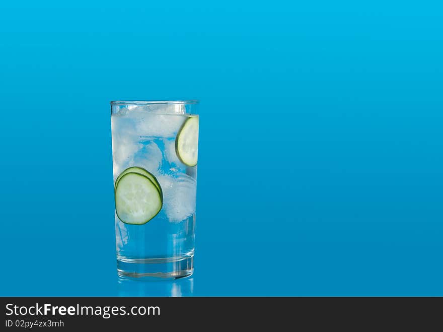 Ice water with cucumbers on blue