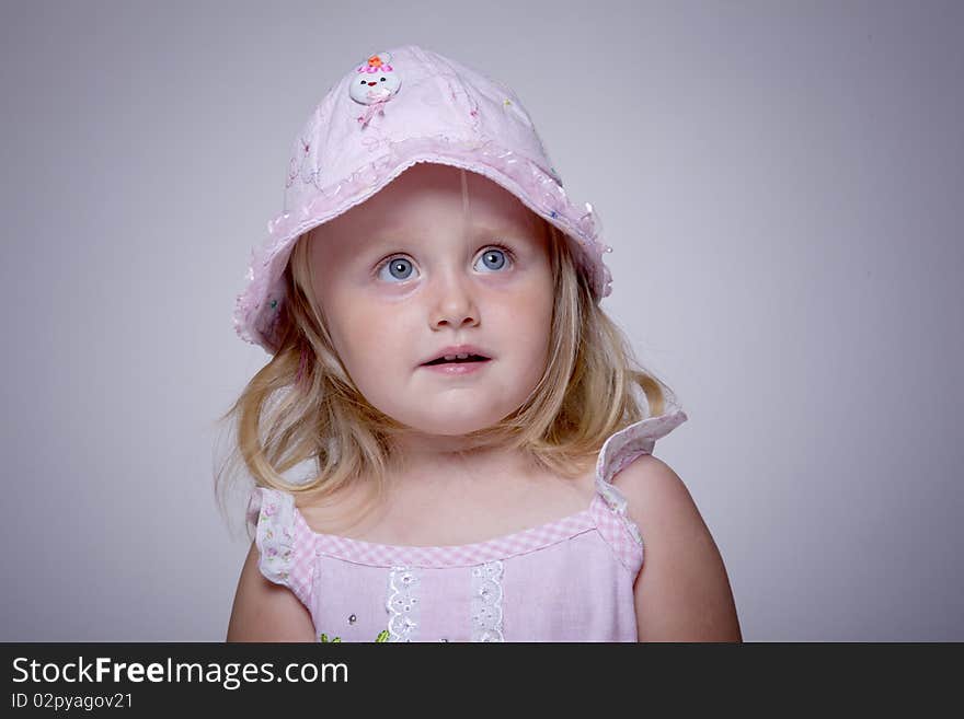 Innocent look portrait of a little girl with pink hat