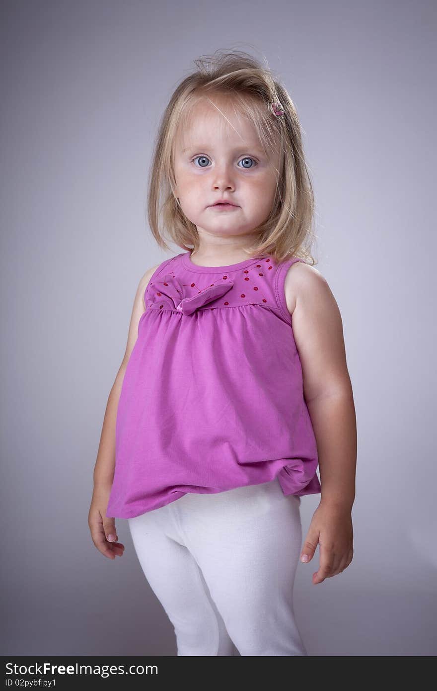 Cute blonde little girl with pink blouse and white pants. Cute blonde little girl with pink blouse and white pants