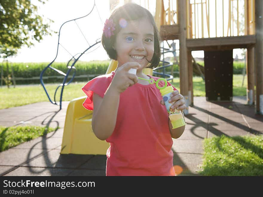 Cute little girl making soap bubbles in a park