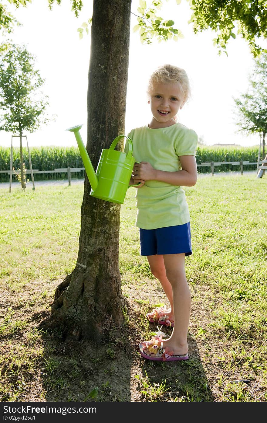 Little girl watering tree