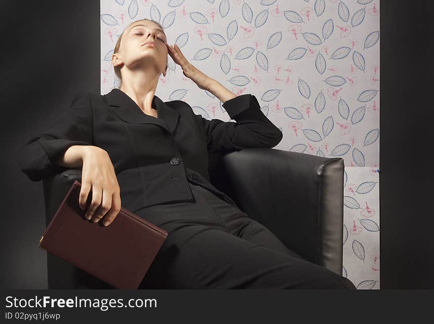 Woman in a black jacket sitting in a leather armchair. Woman in a black jacket sitting in a leather armchair