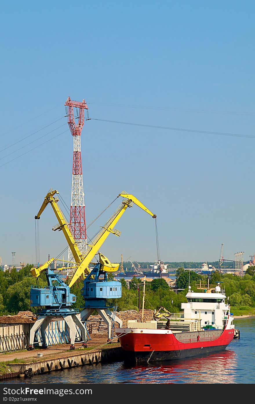 Port cranes load a ship. Port cranes load a ship