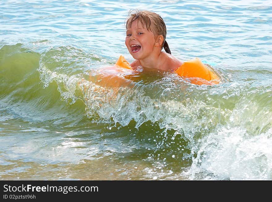 The little girl swims in sea waves