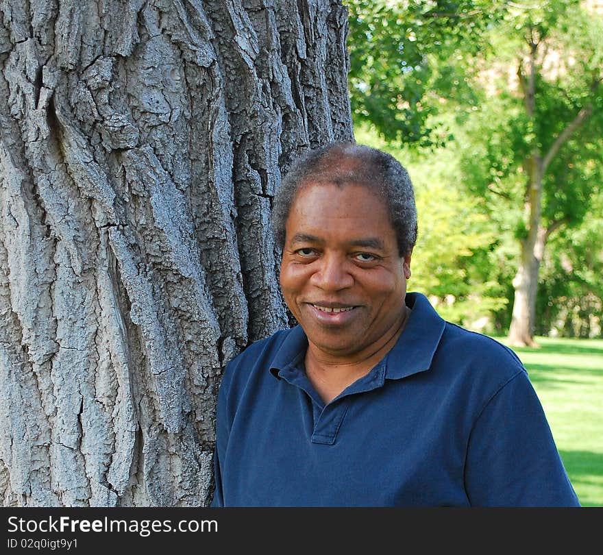 African american man standing by a tree outdoors. African american man standing by a tree outdoors.