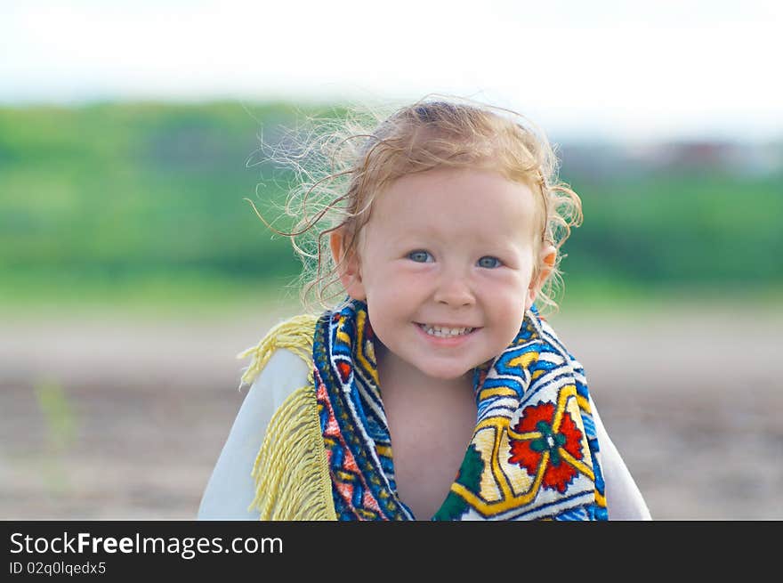 A little girl smiling while sitting on the beach. A little girl smiling while sitting on the beach