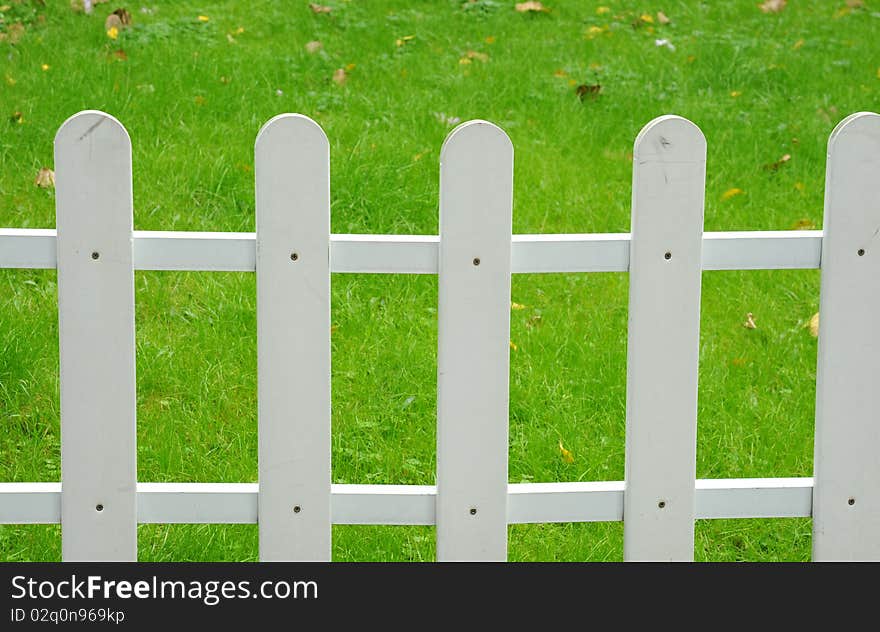 A picket fence with a green lawn as a background