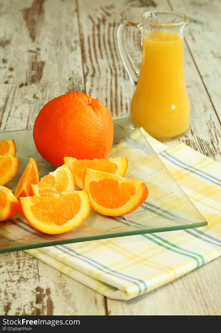 Fresh oranges and orange juice in glass on wooden boards