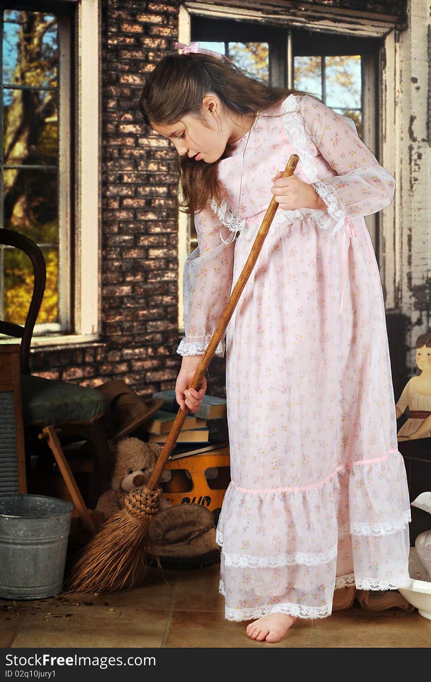 An attractive preteen in an old-fashioned dress, sweeping with an old-fashioned broom in great-grandma's brck shed filled with her old stuff. An attractive preteen in an old-fashioned dress, sweeping with an old-fashioned broom in great-grandma's brck shed filled with her old stuff.