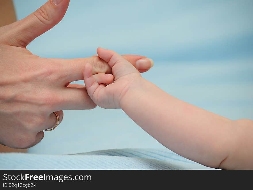 The baby has grasped a finger of mum. The baby has grasped a finger of mum