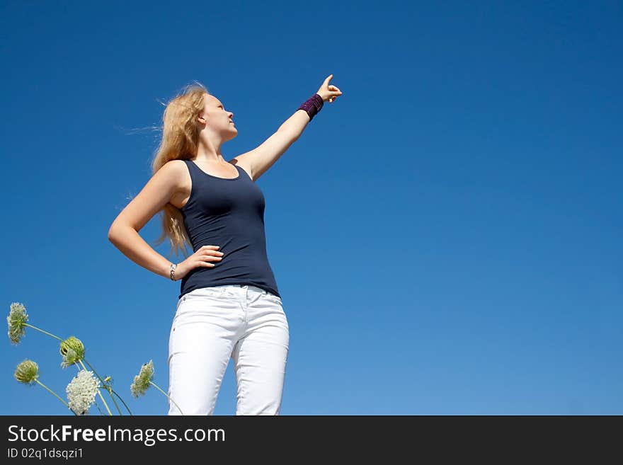 Pretty lady points to the right side in front of a blue sky