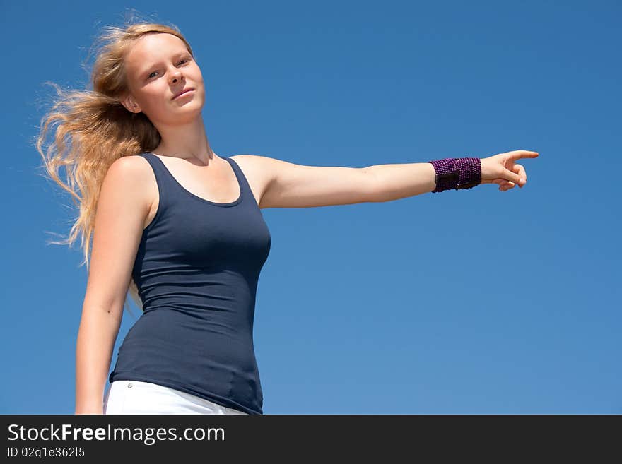 Pretty lady points to the right side in front of blue sky