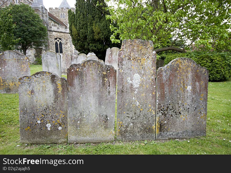 View of four tombstones, with an old church in the background