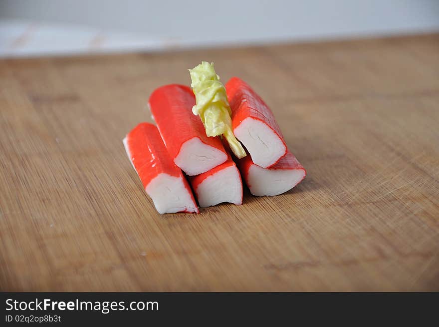 Pile of surimi with lettuce on wood desk. Pile of surimi with lettuce on wood desk