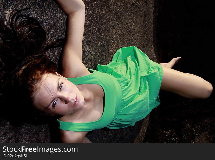 A beautiful young woman in green sundress lying on an islet. Looking at camera. A beautiful young woman in green sundress lying on an islet. Looking at camera.