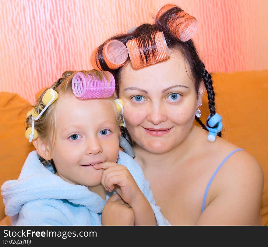 Mother and young daughter, sitting in an embrace on the orange sofa. Mother and young daughter, sitting in an embrace on the orange sofa.