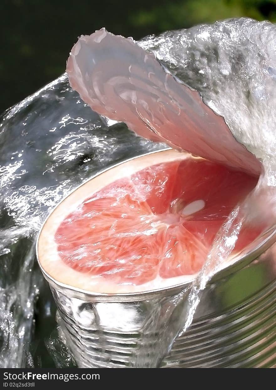 Slice of grapefruit i is filled a opened tin in waterstream, closeup, conceptual. Slice of grapefruit i is filled a opened tin in waterstream, closeup, conceptual