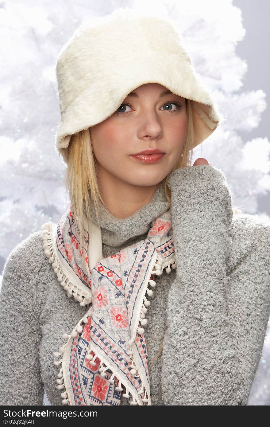 Fashionable Teenage Girl Wearing Cap And Knitwear In Studio In Front Of Christmas Tree. Fashionable Teenage Girl Wearing Cap And Knitwear In Studio In Front Of Christmas Tree