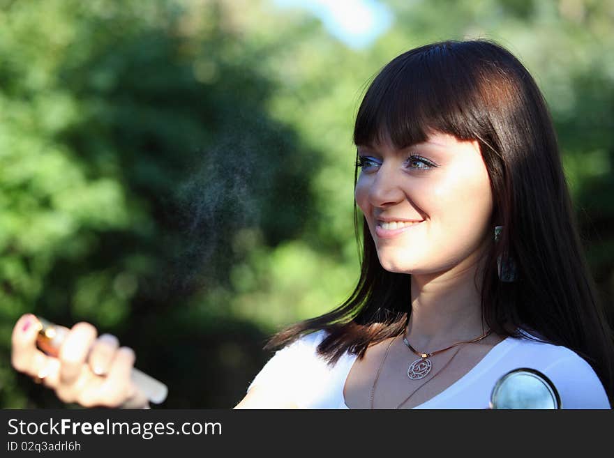 Pretty lady spraying a parfume on nature. Pretty lady spraying a parfume on nature