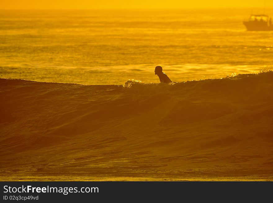 Surfer on wave silhouette at sunrise