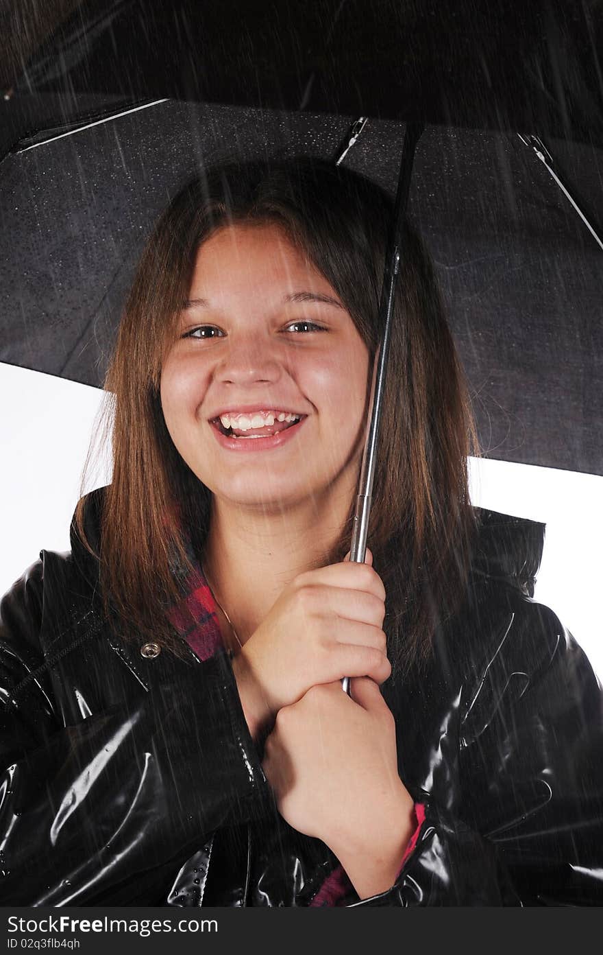 A young teen happily in her raincoat and under a black umbrella  in the rain. A young teen happily in her raincoat and under a black umbrella  in the rain.