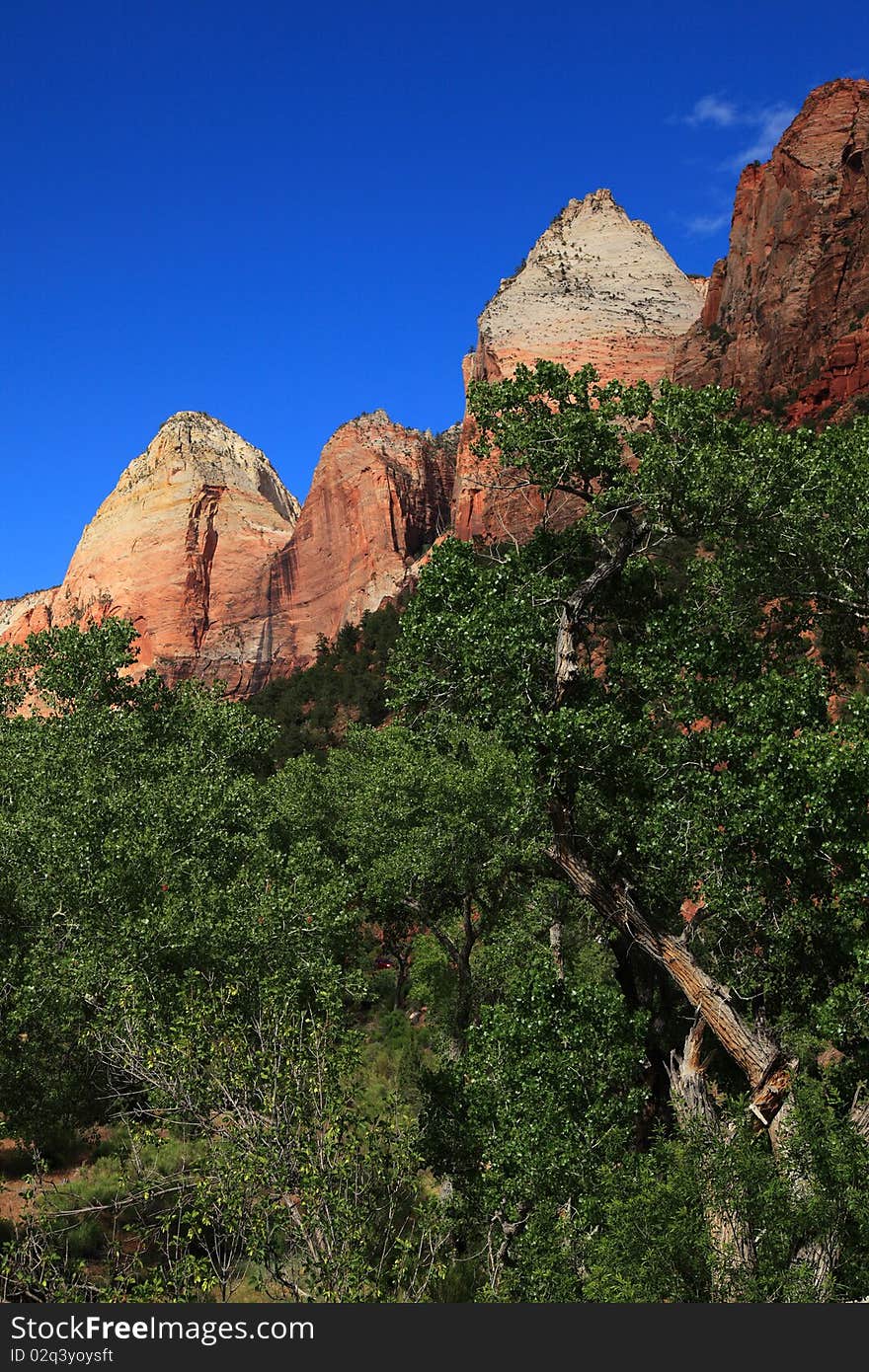 Clear sky, mountain peaks and rich greens compose different levels of colors on the signature of Zion National Park landscape near park entrance. Clear sky, mountain peaks and rich greens compose different levels of colors on the signature of Zion National Park landscape near park entrance.