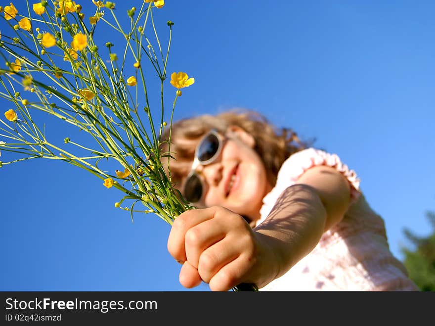 The girl has extended a hand forward with a bouquet from yellow wild flowers against the sky. The girl has extended a hand forward with a bouquet from yellow wild flowers against the sky