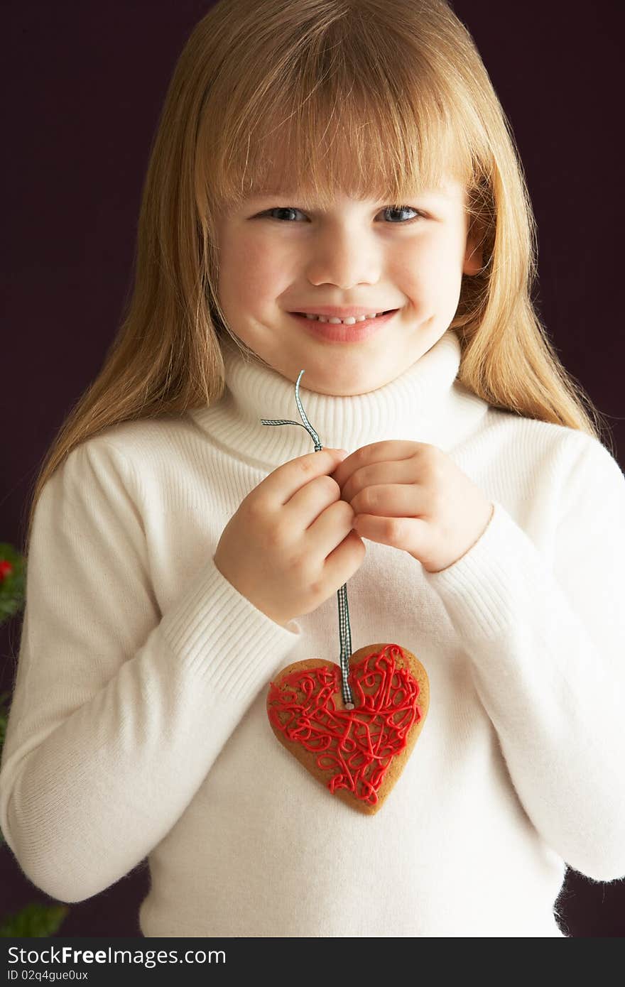 Young Girl Holding Heart Shaped Cookie In Studio