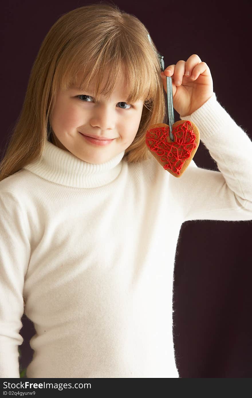 Young Girl Holding Heart Shaped Cookie In Studio