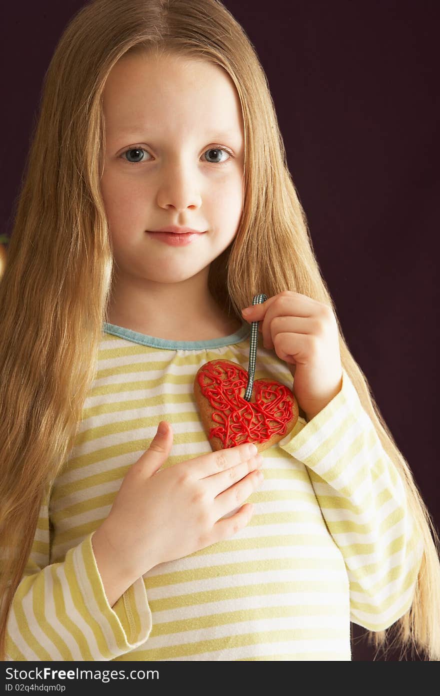 Young Girl Holding Heart Shaped Cookie In Studio