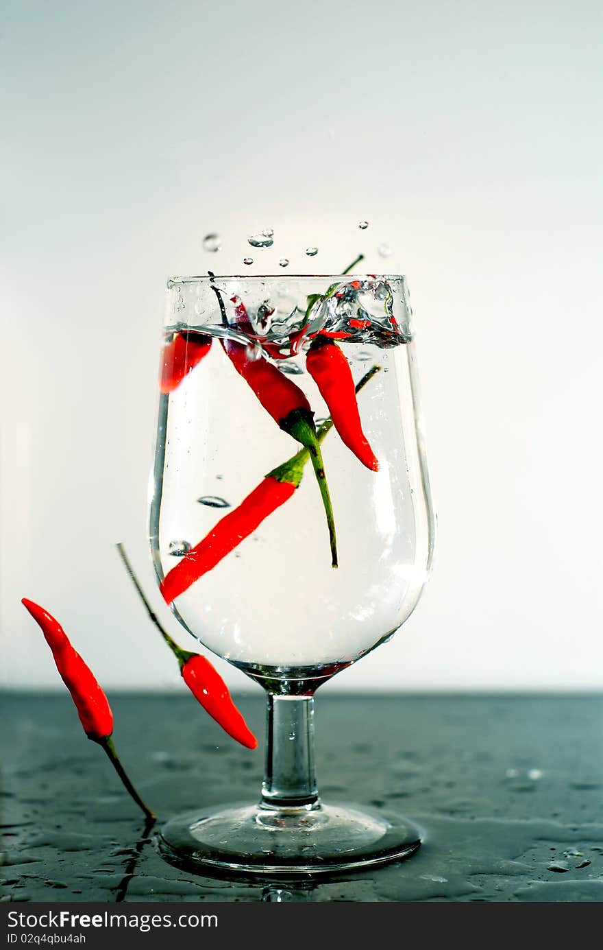 A handful of chili dropped into a glass of water creating an interesting abstract of a picture. A handful of chili dropped into a glass of water creating an interesting abstract of a picture.