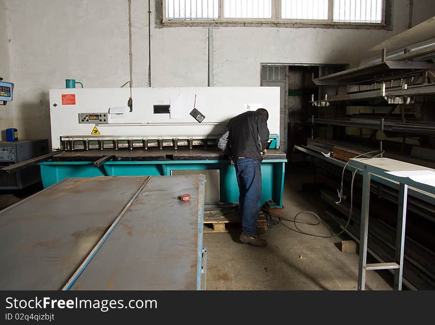 Metalworker at work in his workshop forging the iron with a machine. Metalworker at work in his workshop forging the iron with a machine