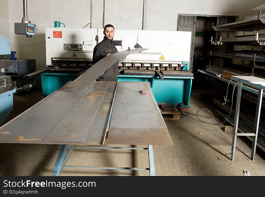 Metalworker at work in his workshop forging the iron with a machine. Metalworker at work in his workshop forging the iron with a machine