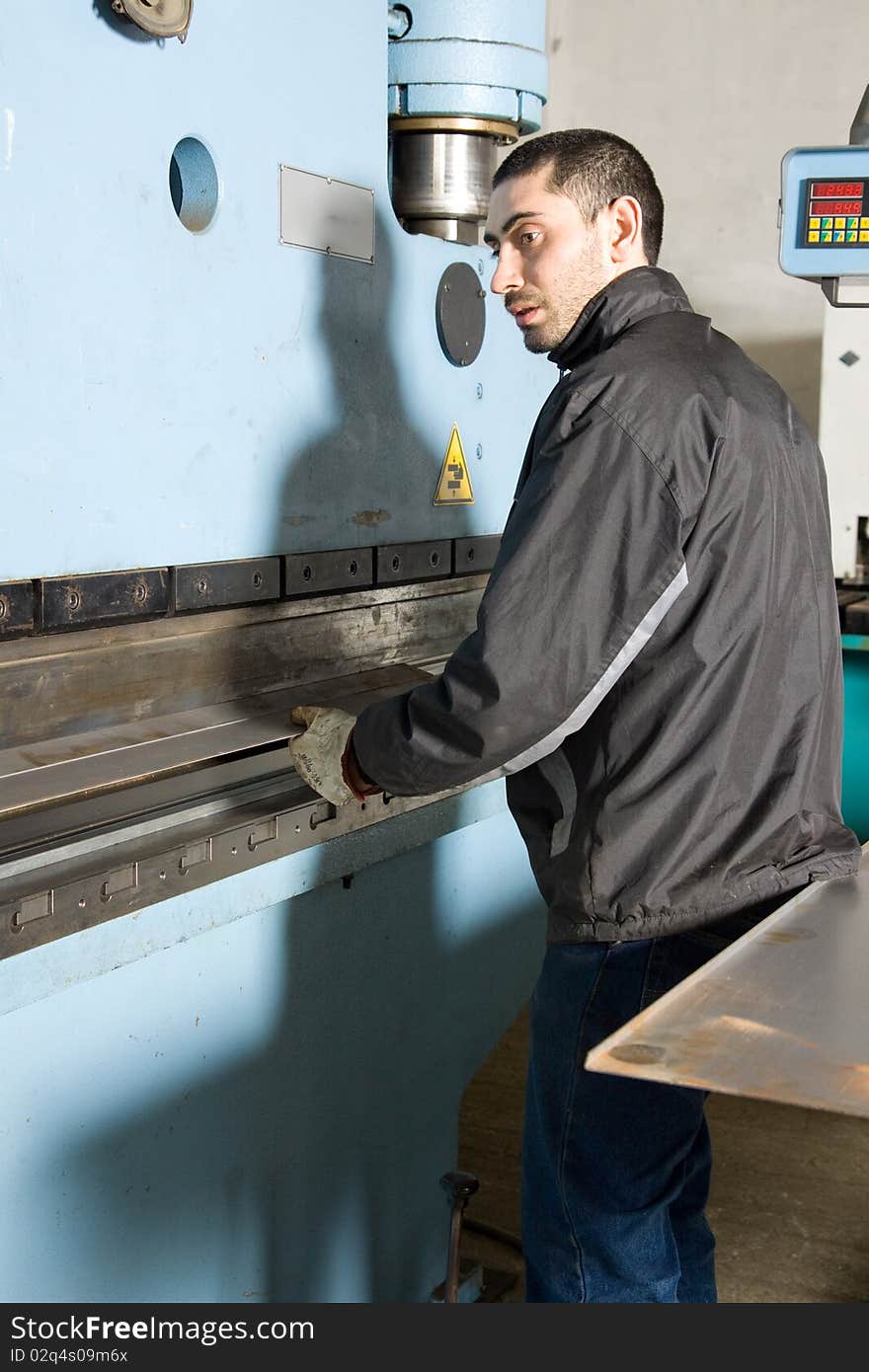 Metalworker at work in his workshop forging the iron with a machine. Metalworker at work in his workshop forging the iron with a machine