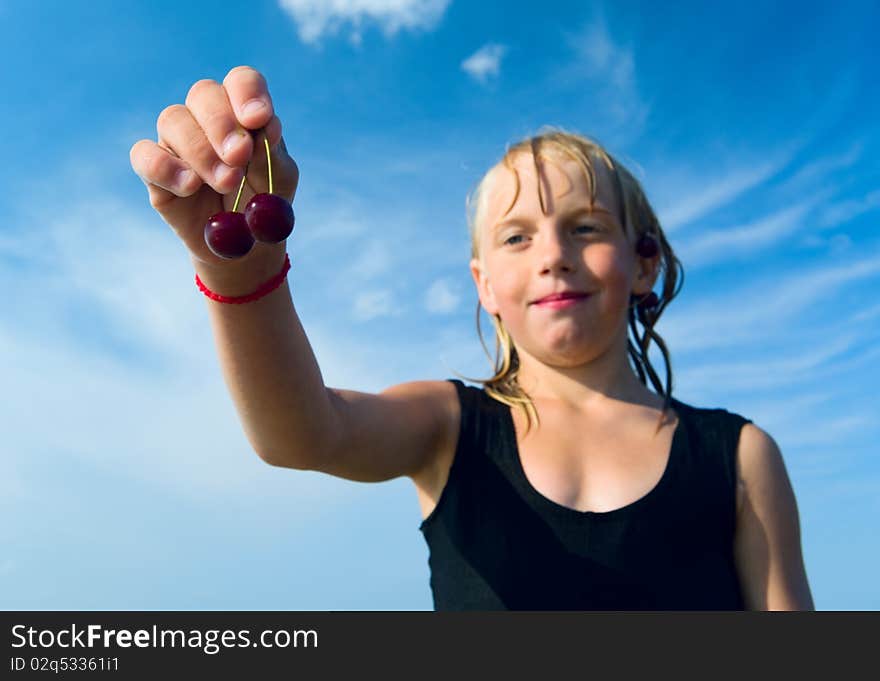 Focus is on the hand with cherry, wet girl on the blue sky background. Focus is on the hand with cherry, wet girl on the blue sky background.