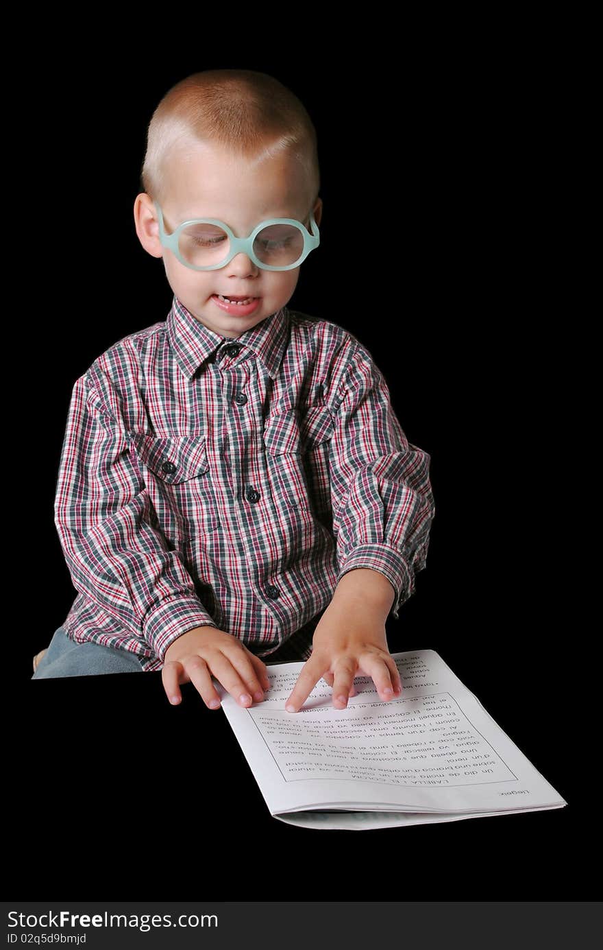 Cute boy with glasses pointing at paper isolated on a black background