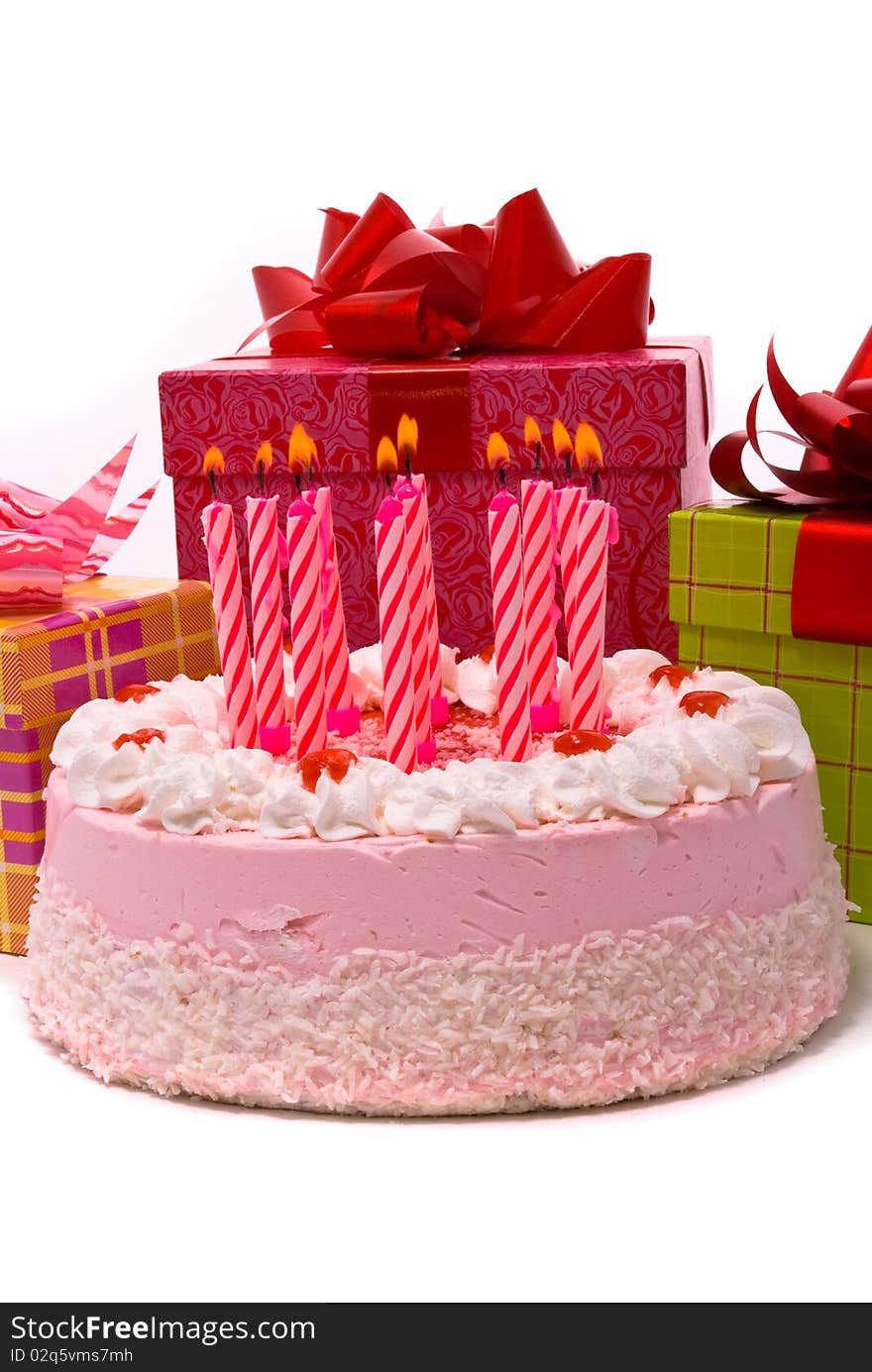 Pink pie with eleven candles and gifts in boxes on a white background