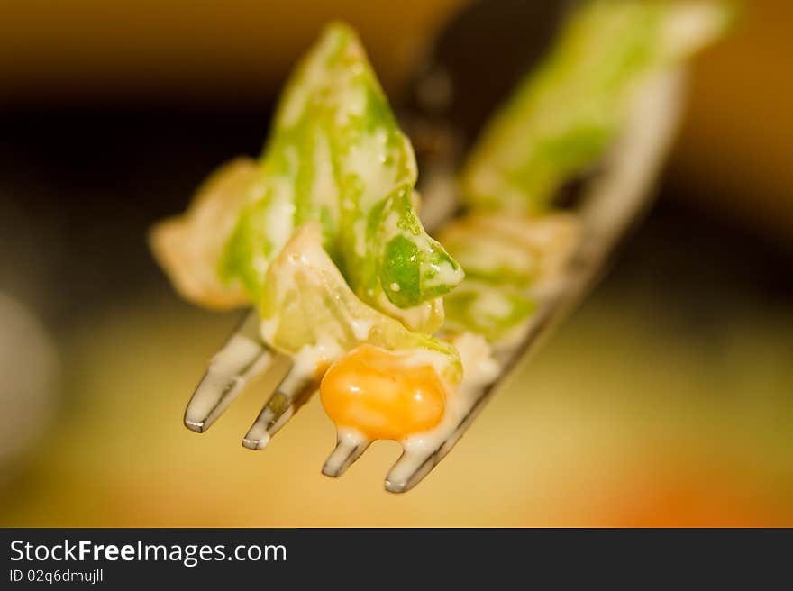 Macro of a fork containing fresh salad with corn and mayonnaise sauce. Macro of a fork containing fresh salad with corn and mayonnaise sauce