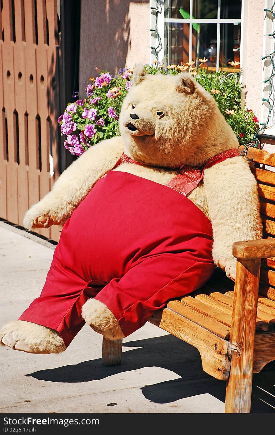 Big teddy bear in red pants sitting on bench. Big teddy bear in red pants sitting on bench