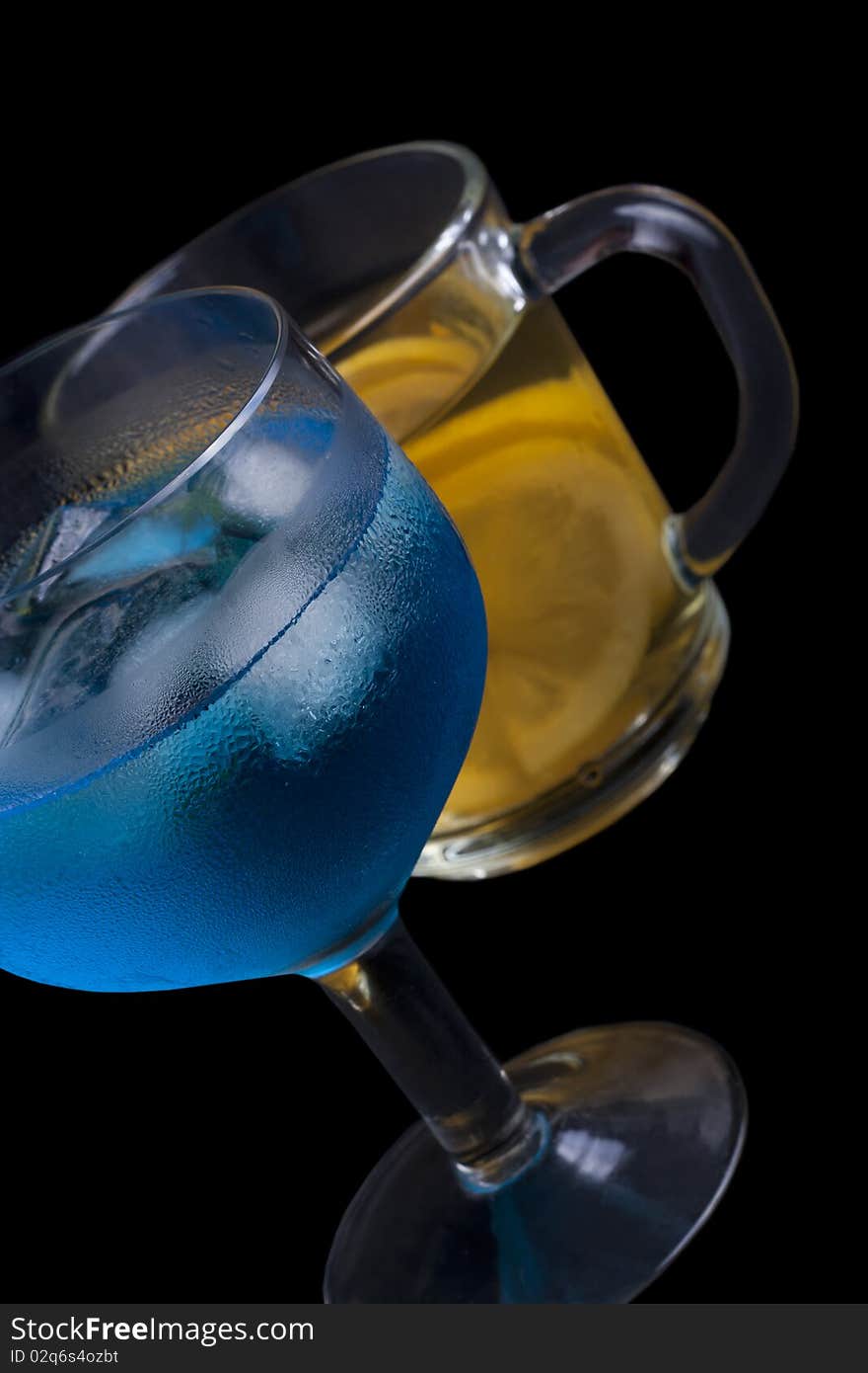 Ice tea and a blue drink with ice in a glass on a black background. Ice tea and a blue drink with ice in a glass on a black background