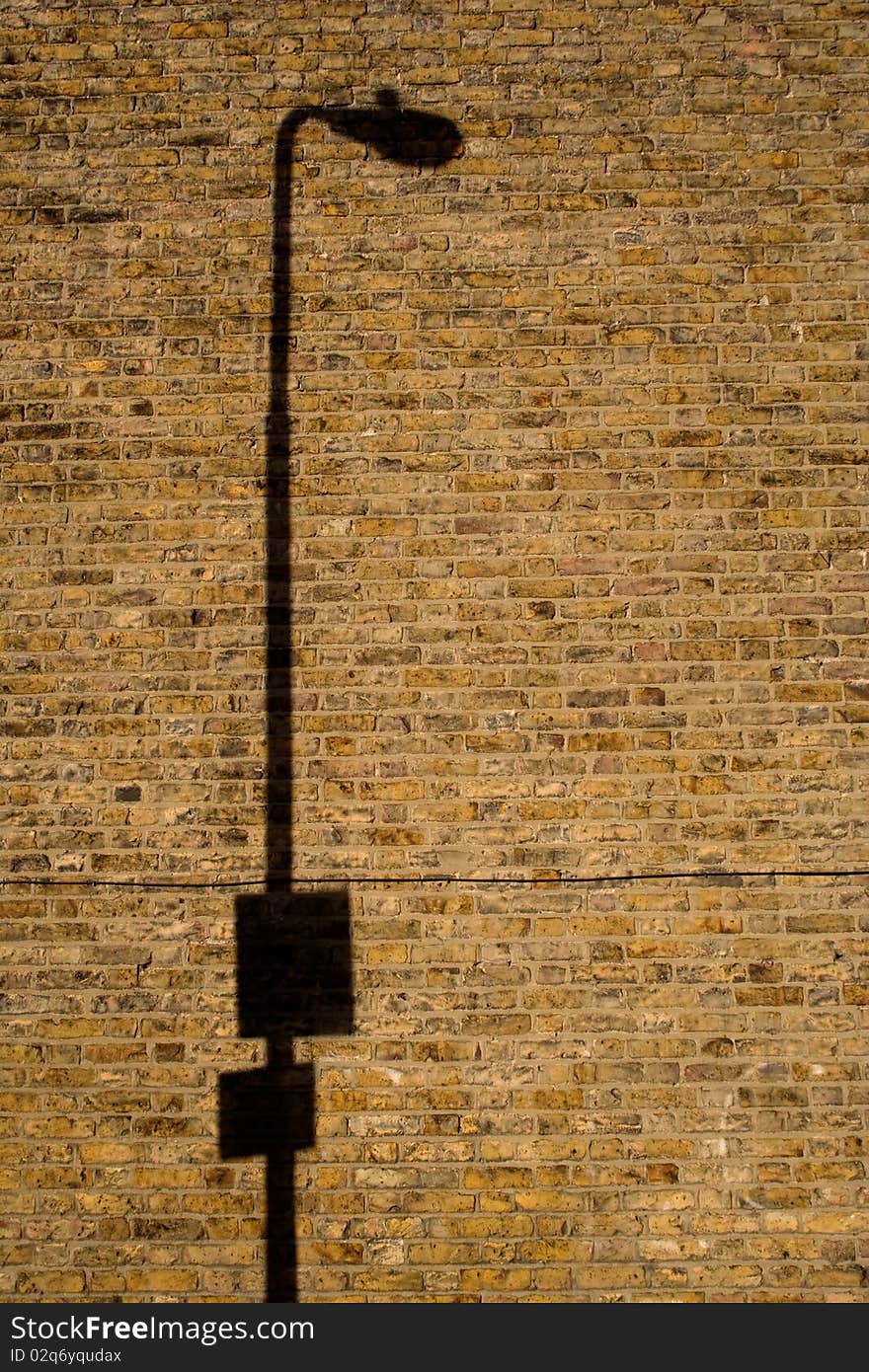 Shadow of a lamp post cast onto a brick wall. Shadow of a lamp post cast onto a brick wall.