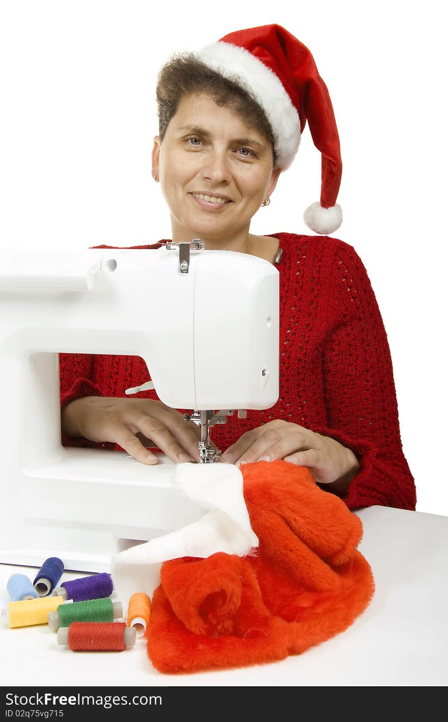 Woman sewing a fur coat for Santa Claus on the sewing machine