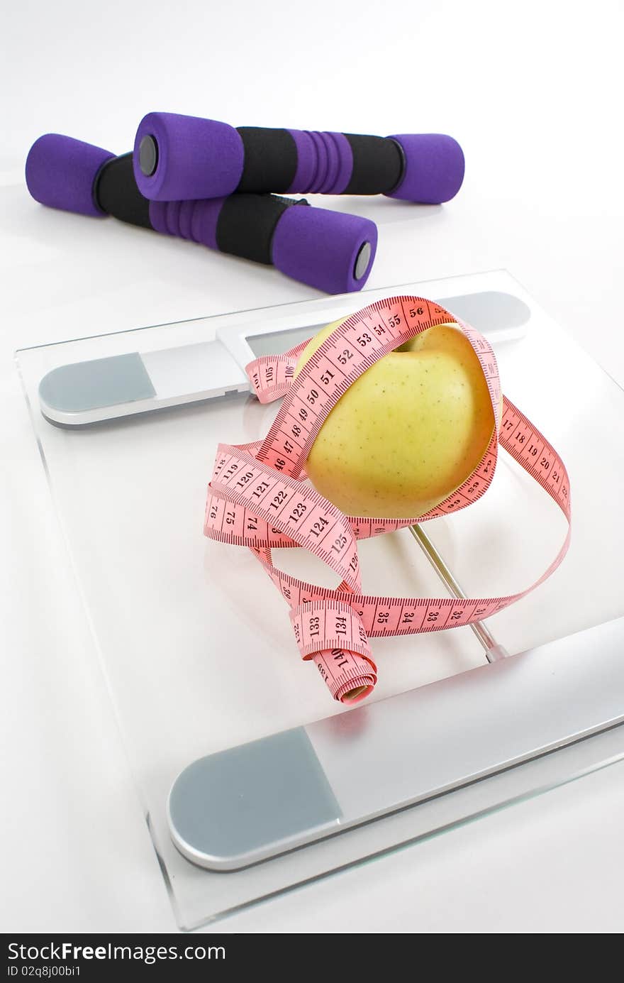 Apple tighten with measure tape, dumbbell, and scale isolated on white