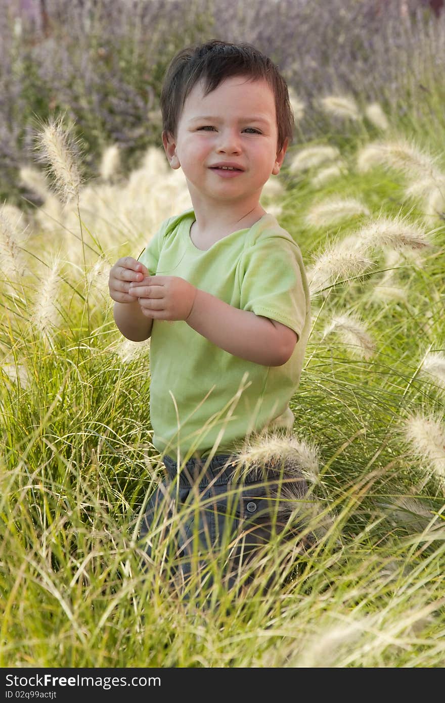 A small child standing in a long grass in a Mediterranean garden. A small child standing in a long grass in a Mediterranean garden.